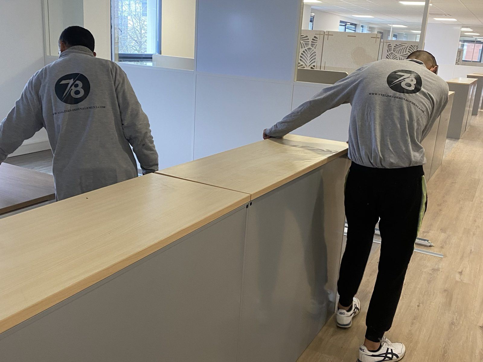 Deux déménageurs alignant des meubles de rangement