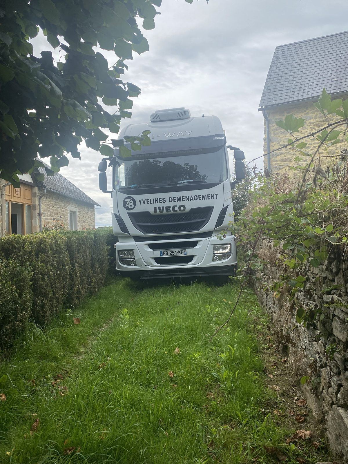 Tracteur Iveco dans un chemin étroit entre deux maisons