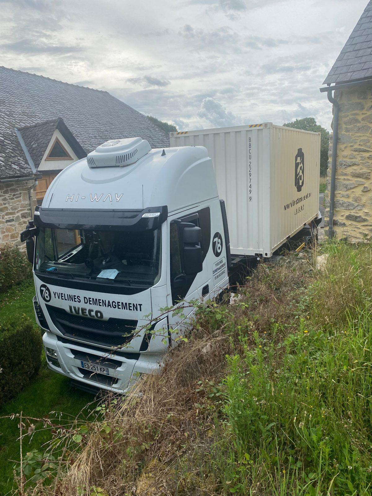 Camion avec conteneur livrant une maison en pierre à la campagne