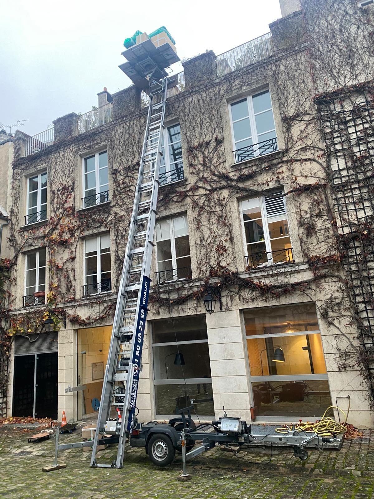 Monte-meuble dressé contre une façade couverte de lierre