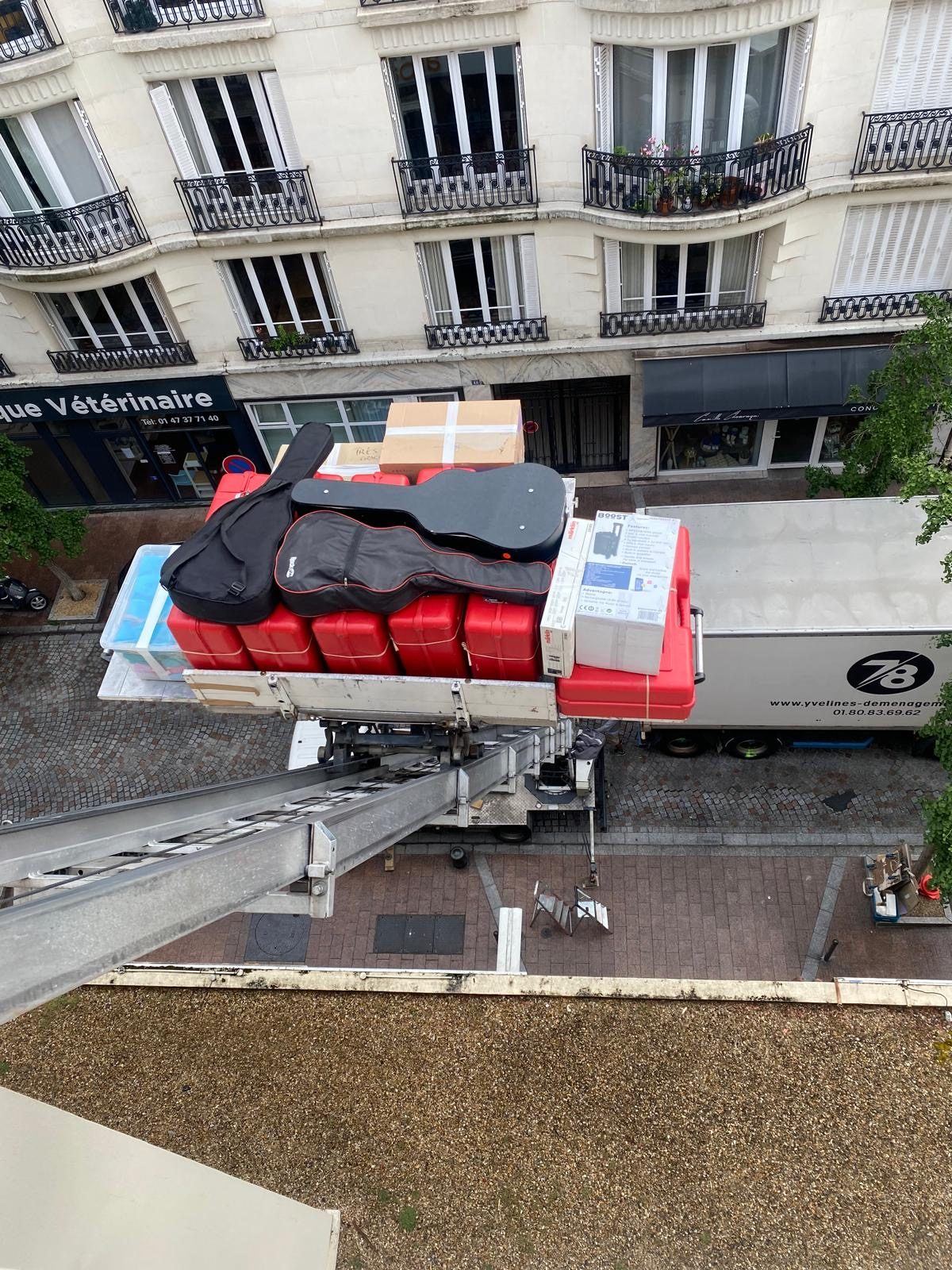 Valises, guitares et cartons sur le plateau du monte-meuble