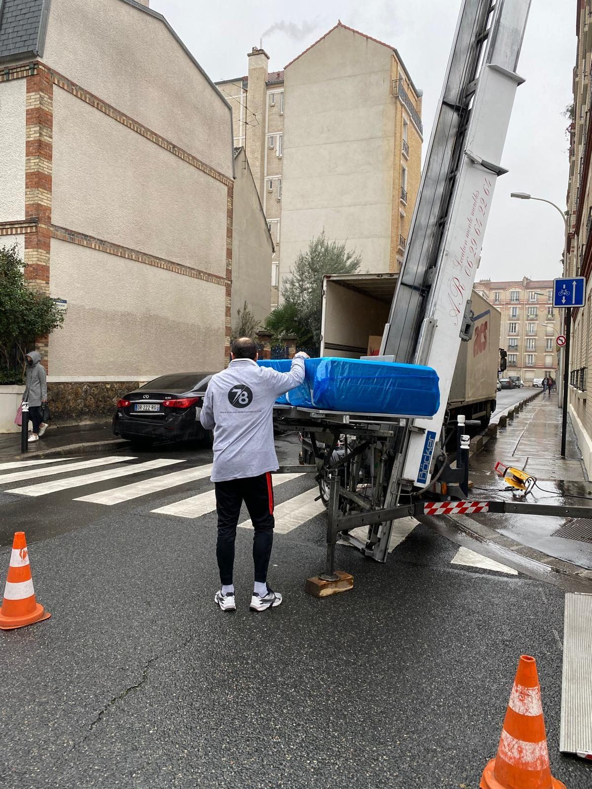 Déménageur guidant un colis sur le monte-meuble